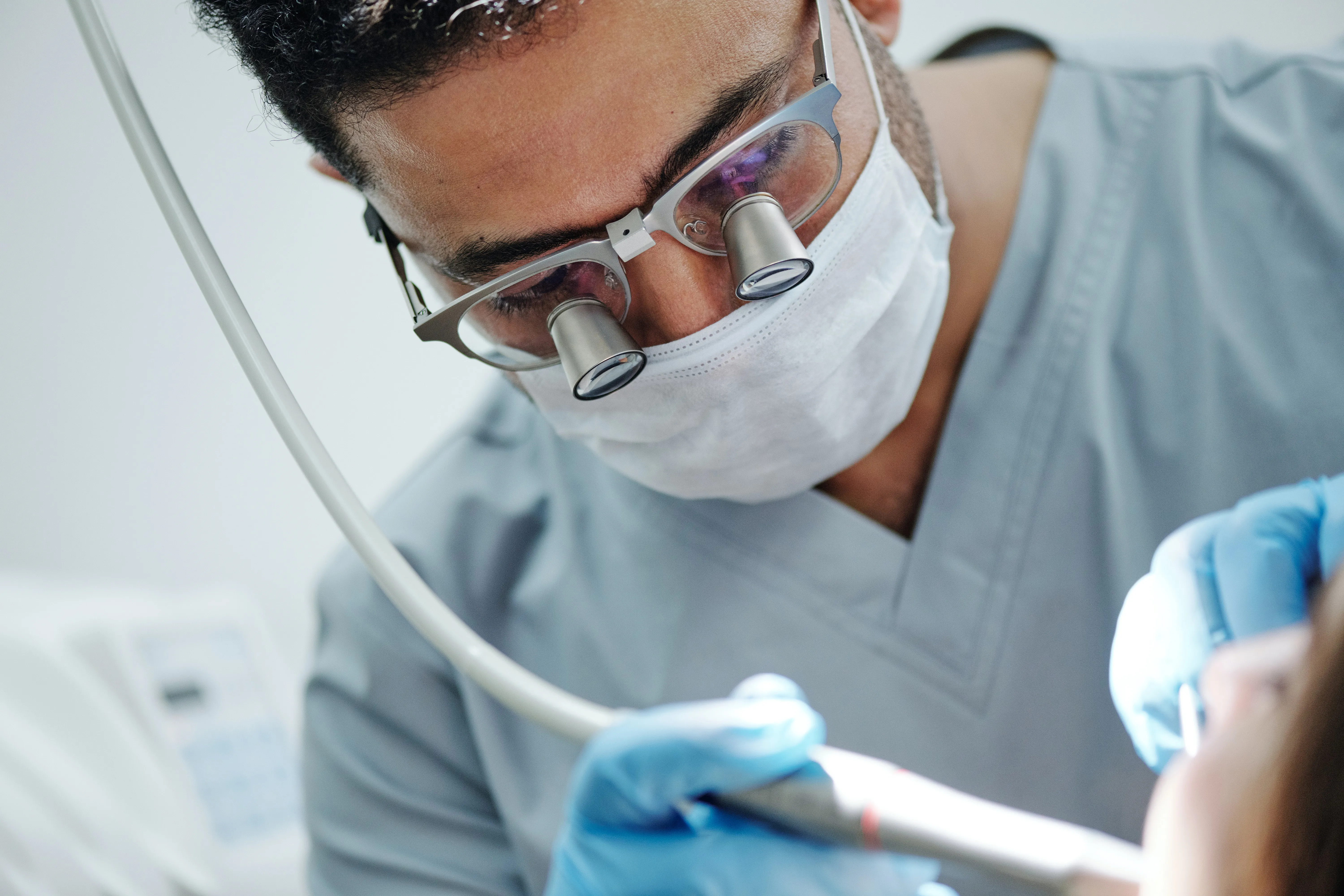 A dentist wearing magnifying loupes during a precise treatment